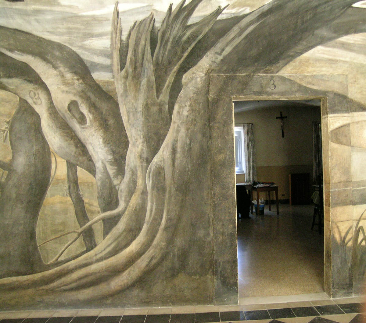 En quittant le point de vue privilégié et en s’avançant dans le couloir, l’anamorphose apparait dans sa déformation. Une tour, des maisons, un port constitue le paysage qui s’inscrit dans ce qu’étaient les plis du manteau du Saint. En bas, Saint François de Paule au milieu des bateaux marche sur les eaux du détroit de Messine, porté par son manteau.